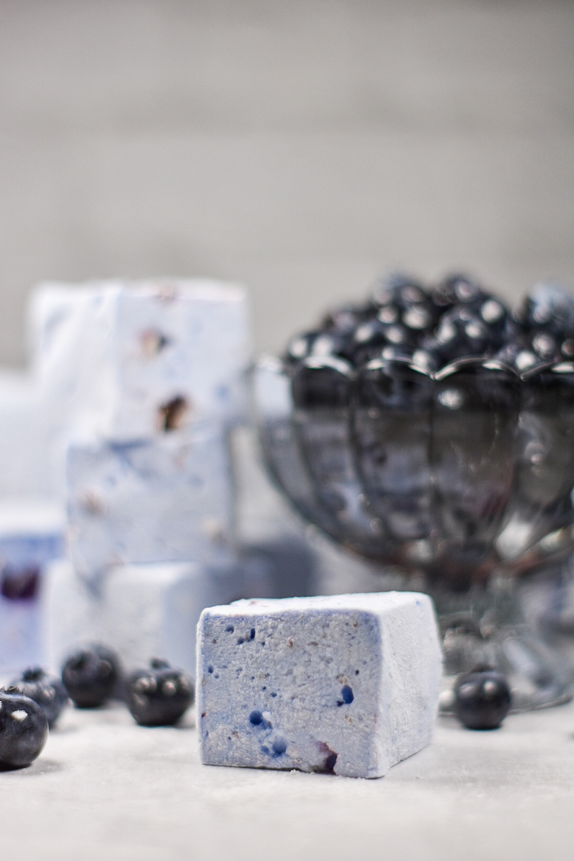 A blueberry marshmallow with a dish of berries in the background
