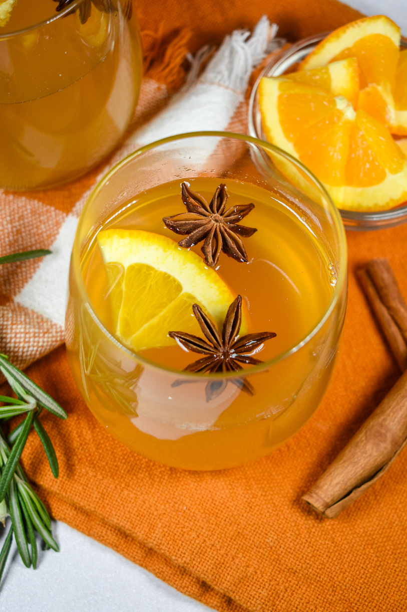 a glass of mulled white wine with star anise and orange slices