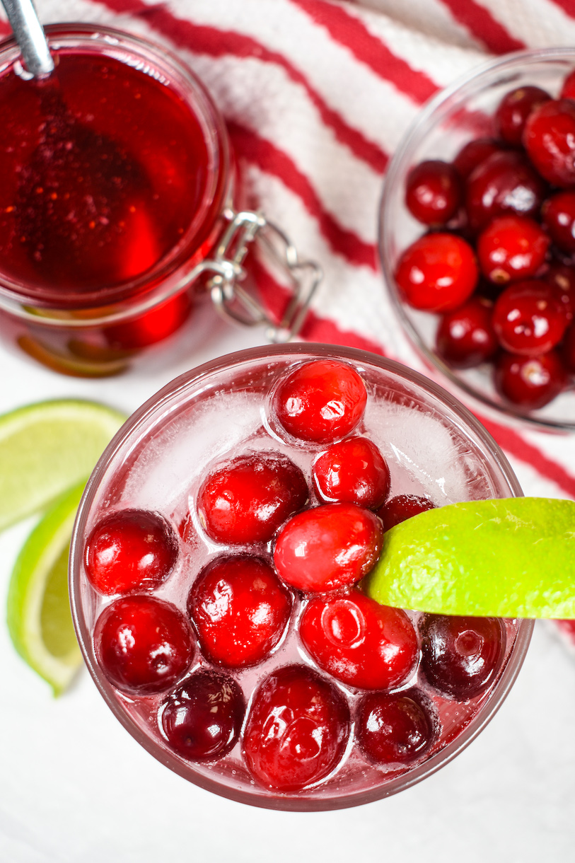 Looking down at a drink garnished with cranberries and a lime wedge