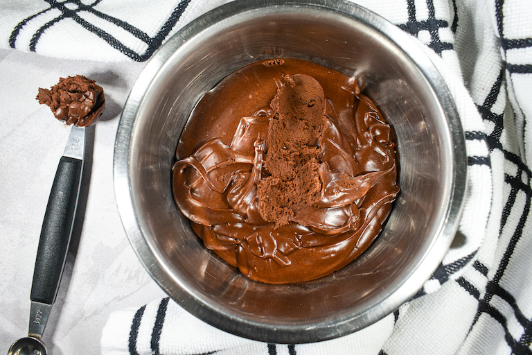 A bowl of chocolate ganache, a melon baller, and a plaid tea towel