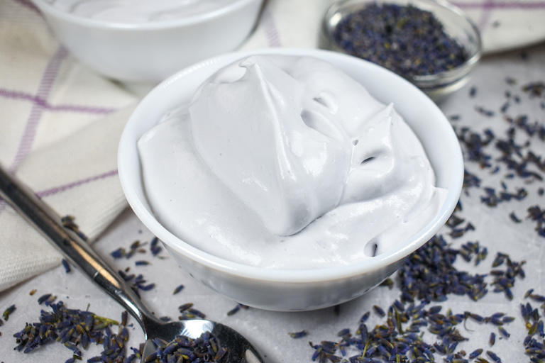 A dish of lavender whipped cream surrounded by dried lavender buds
