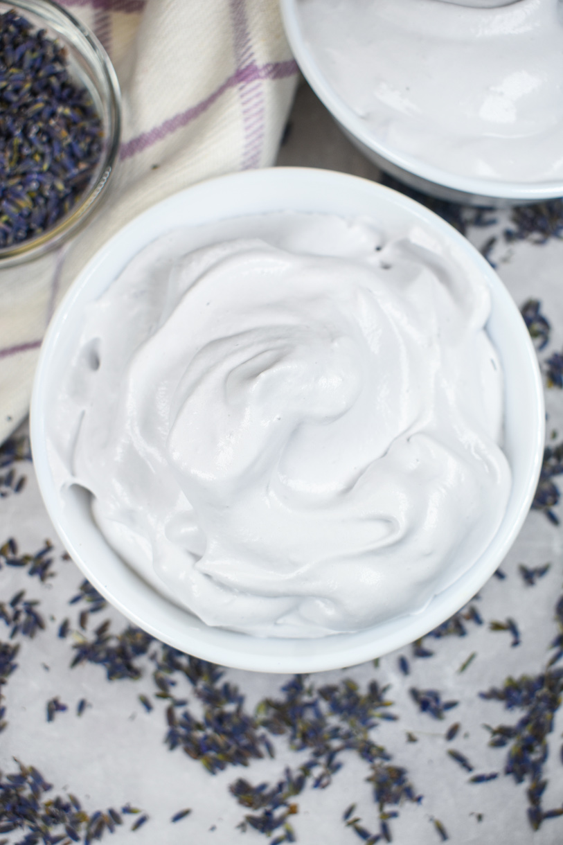 Looking down at a bowl of whipped cream surrounded by lavender buds