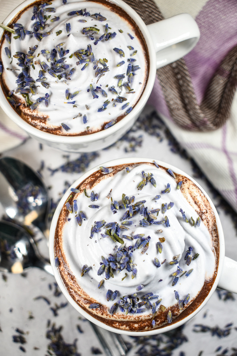 Mugs of lavender hot cocoa with whipped cream and dried lavender flowers