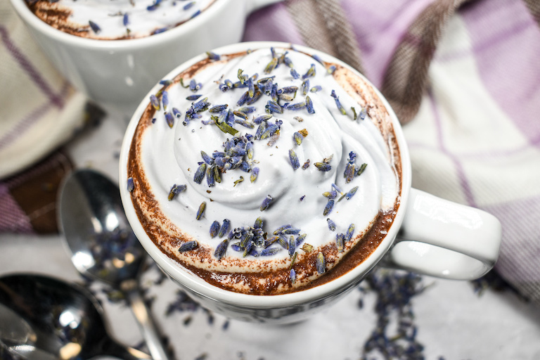 A mug of lavender hot chocolate garnished with whipped cream and dried lavender