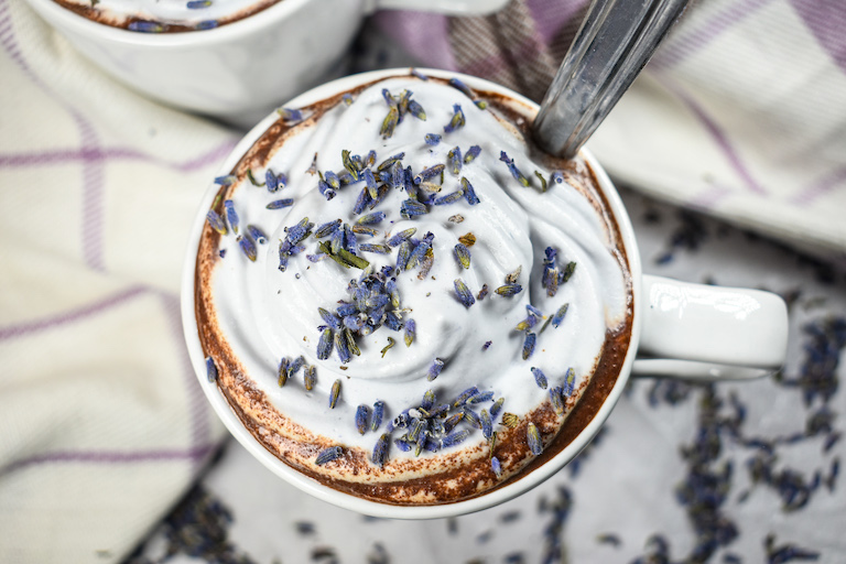Looking down at a mug of lavender hot chocolate with lavender whipped cream and dried lavender buds