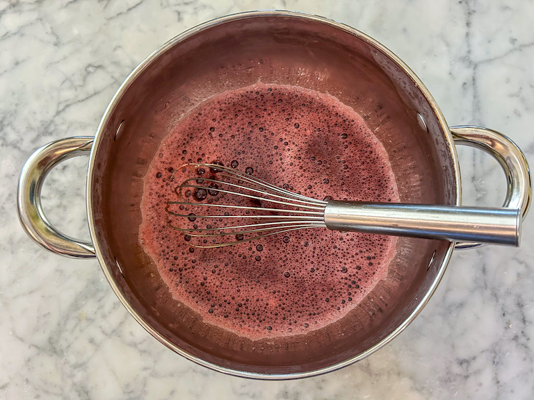 A whisk in a pan of cranberry juice