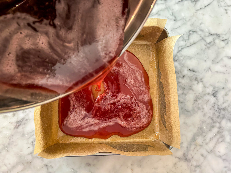 Pouring cranberry candy mixture into a pan