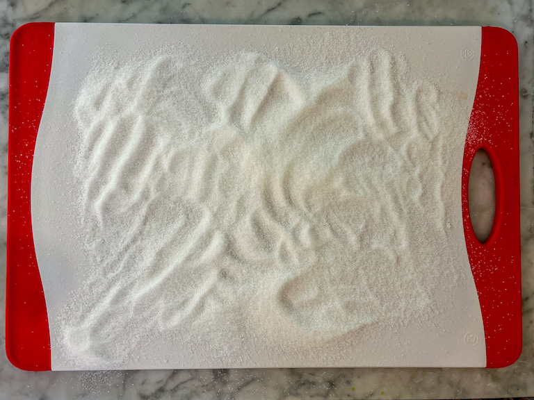 A cutting board coated in sugar