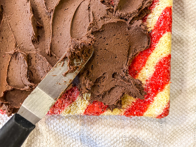 Palette knife spreading chocolate buttercream on a Christmas Swiss roll