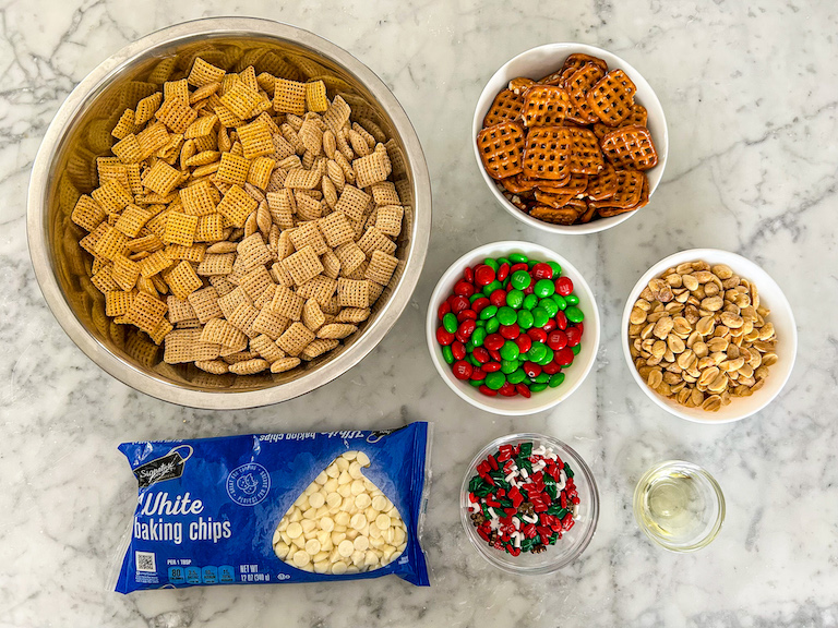 Christmas Chex mix ingredients on a marble surface