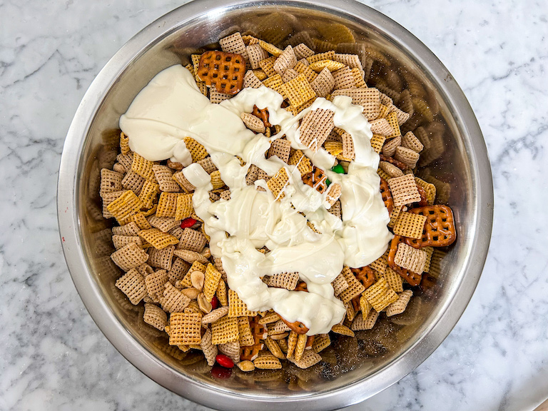 Cereal mix ingredients with melted white chocolate drizzled on top