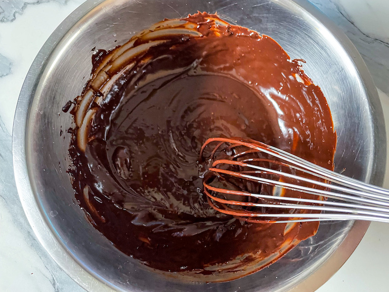 Whisking cream into a bowl of melted chocolate