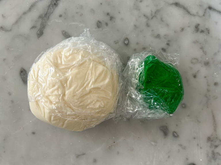 Balls of white and green soft peppermint dough wrapped in clingfilm