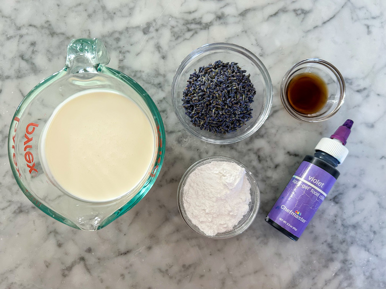 Ingredients for making this lavender whipped cream recipe, arranged on a marble countertop