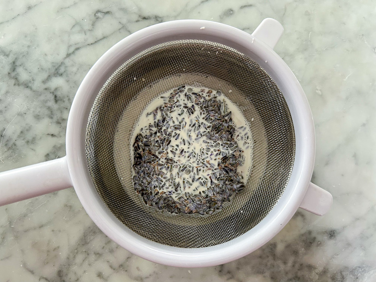 Fine mesh strainer separating lavender buds from cream