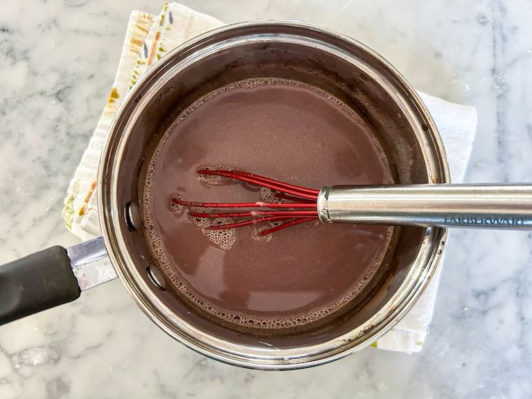 A saucepan of hot chocolate on a marble countertop