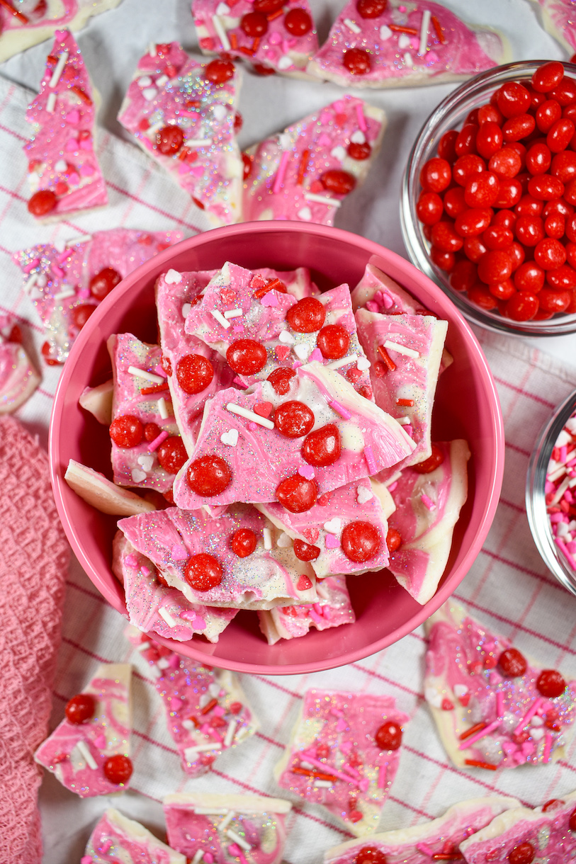 a dish of pink and red cinnamon bark next to a small dish of cinnamon candies