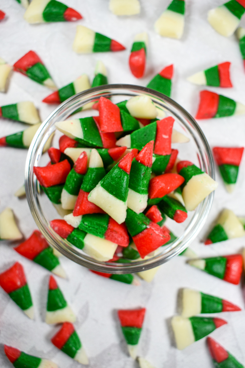 a dish of christmas candy corn on a white surface surrounded by more candy corn
