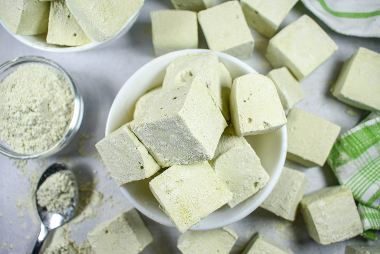 A bowl of matcha green tea marshmallows on a white surface