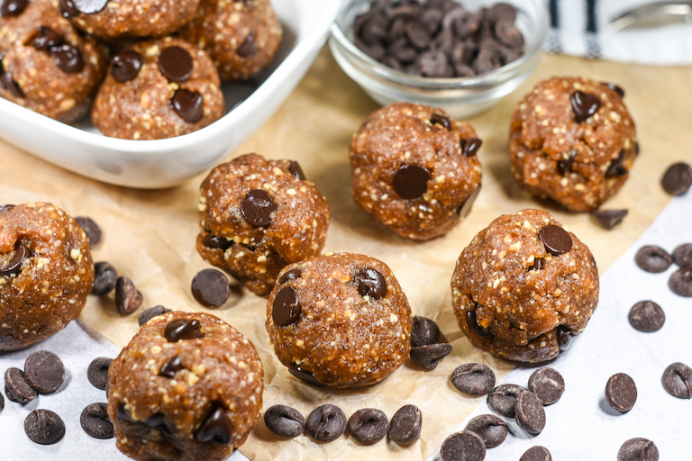 Chocolate chip date balls and chocolate chips arranged on a sheet of parchment