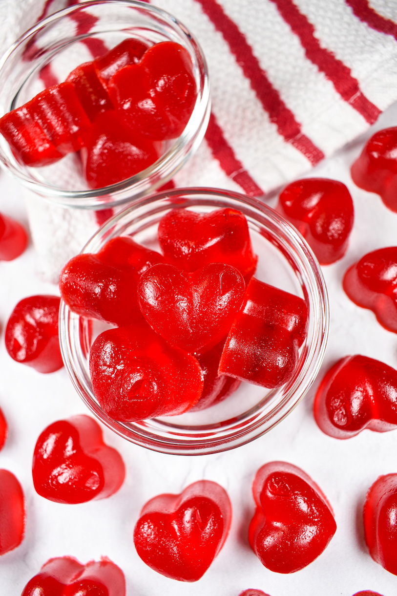 a dish of red gummy hearts on a white surface