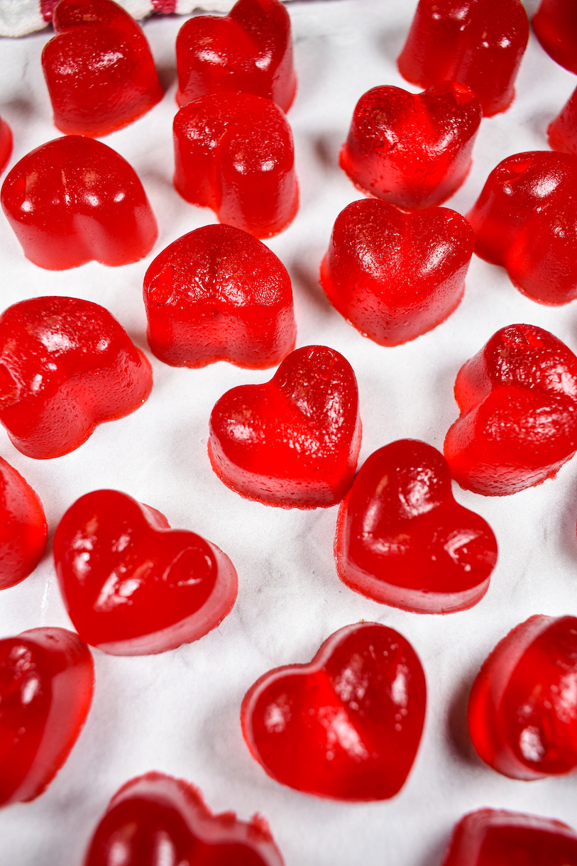 Red gummy hearts on a white surface