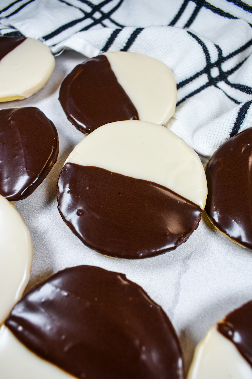 Black and white cookies on a white surface with a plaid towel