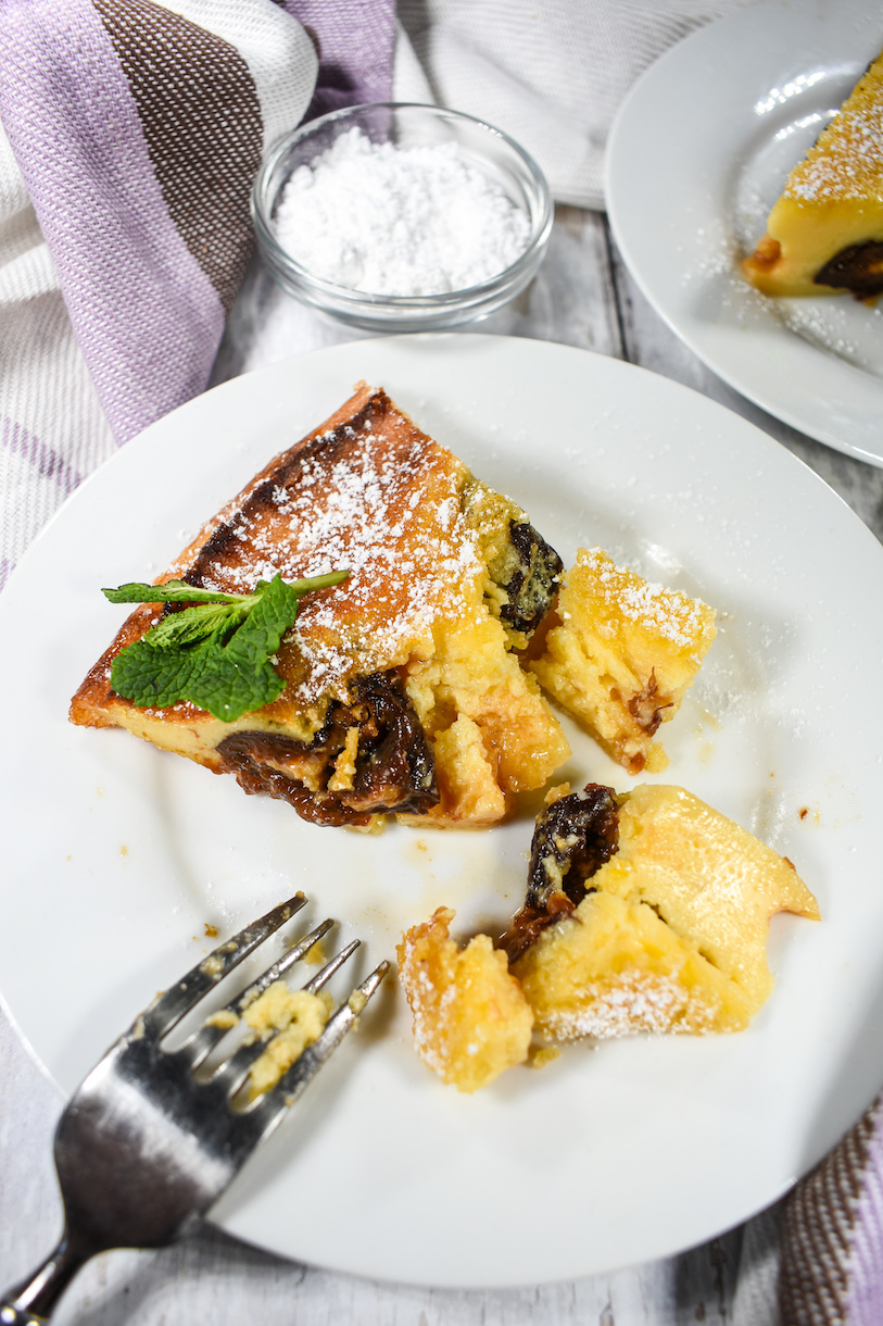 Slice of clafoutis with a bite missing, on a plate with a dessert fork