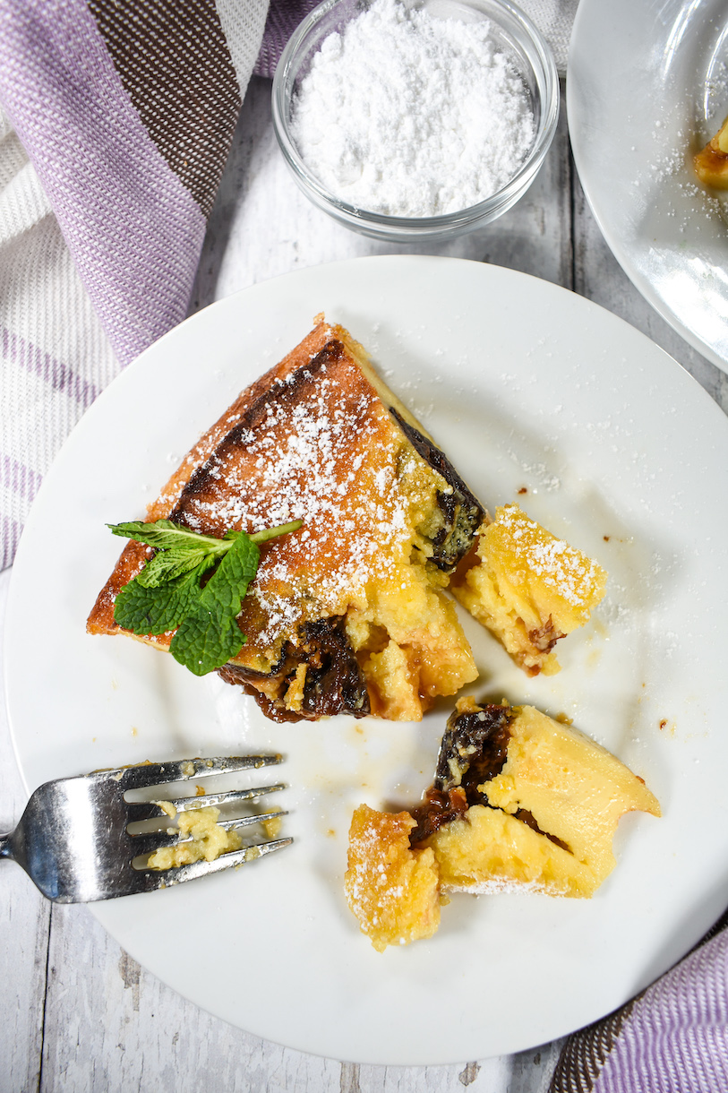 a slice of prune clafoutis on a plate with a fork