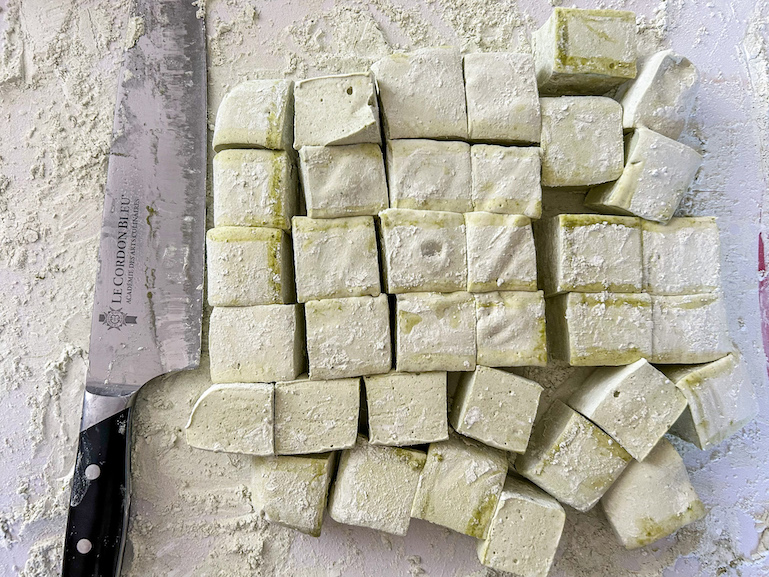 Matcha marshmallows on a cutting board with a knife