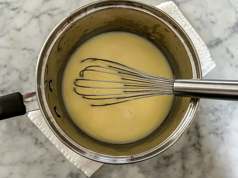 Milk and melted white chocolate in a pan with a whisk