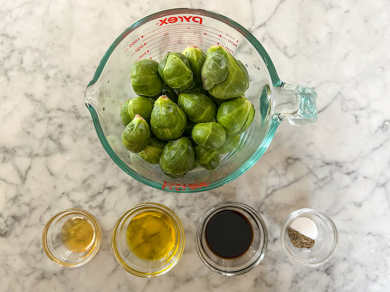 Ingredients for making roasted sprouts, arranged on a marble surface