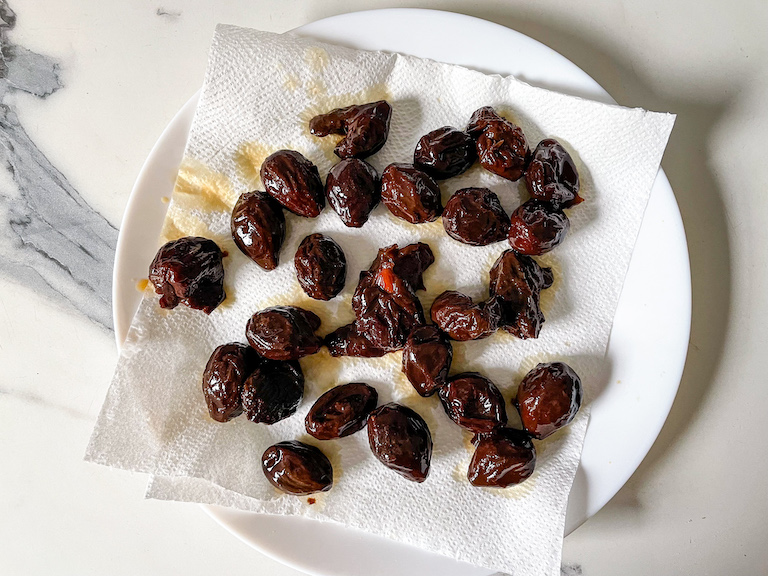 Prunes drying on a paper towel lined plate