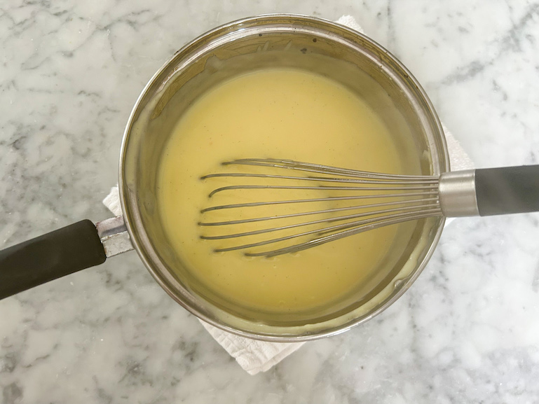 Homemade vanilla pudding in a pan with a whisk