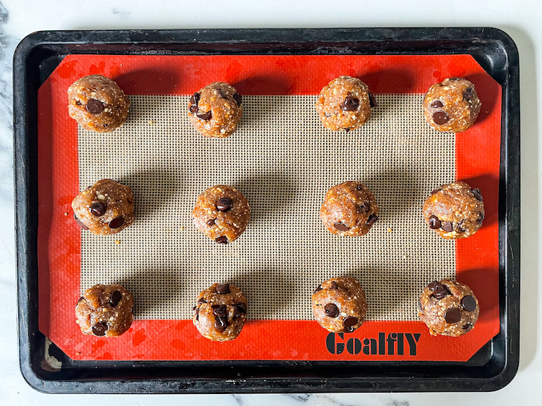 Cookie dough date balls arranged on a silicone baking mat