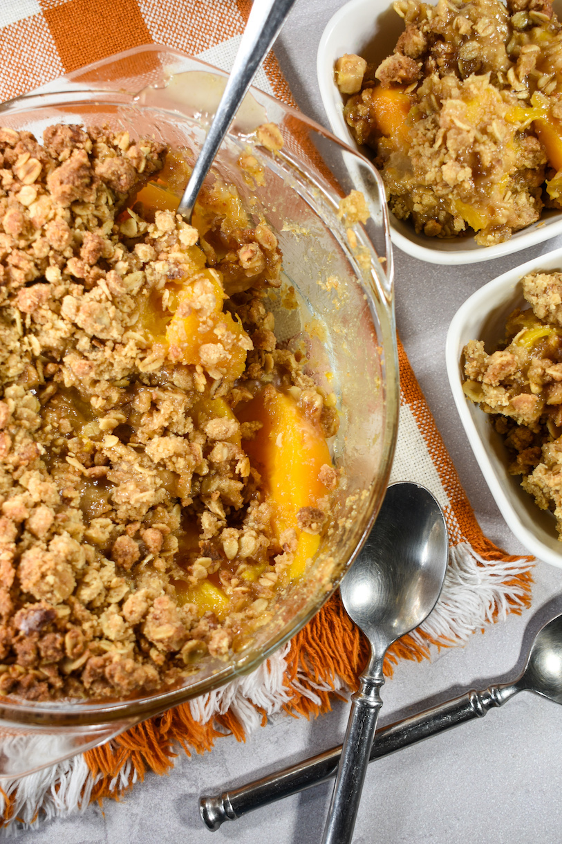 ginger peach crisp on a plaid towel with two spoons
