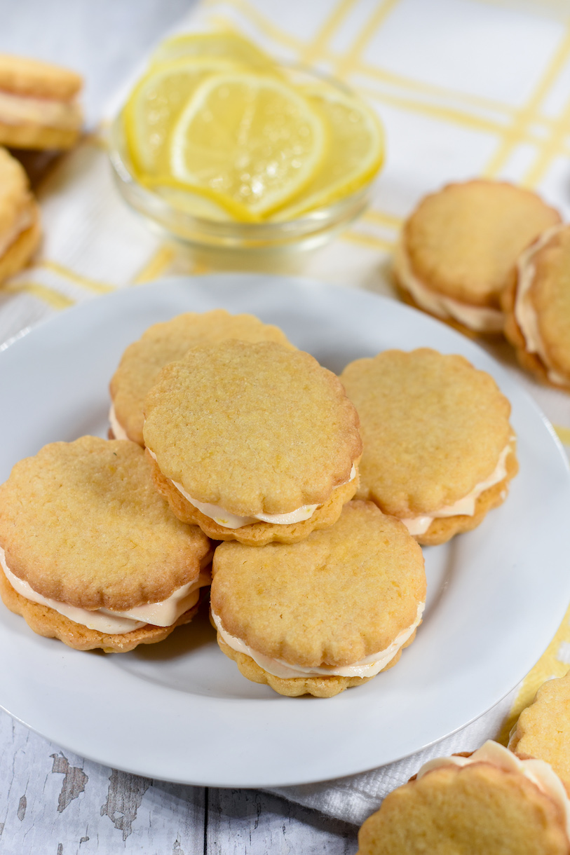 A plate of lemon cream cookies and a dish of lemon slices