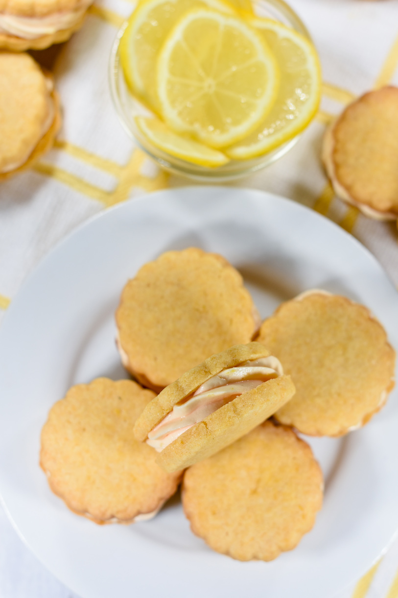 A plate of lemon cream biscuits and a dish of lemons