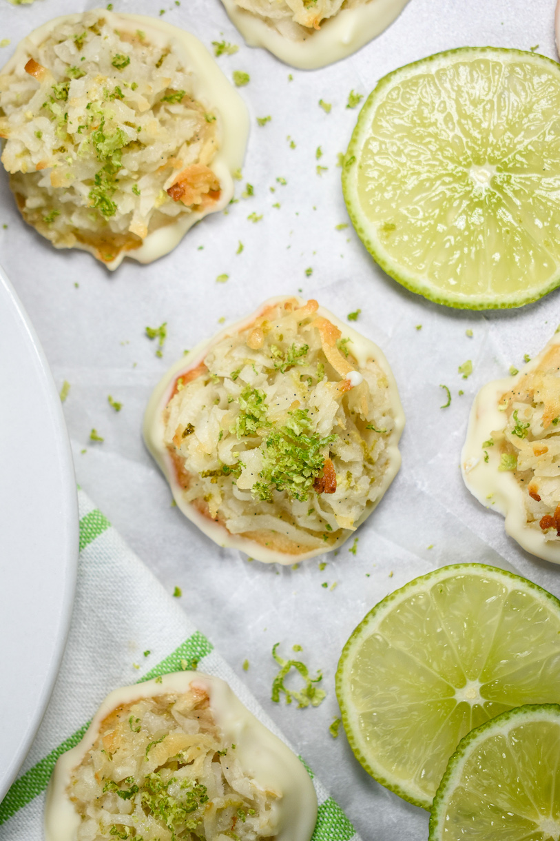 Looking down at coconut macaroons and lime slices on a white surface