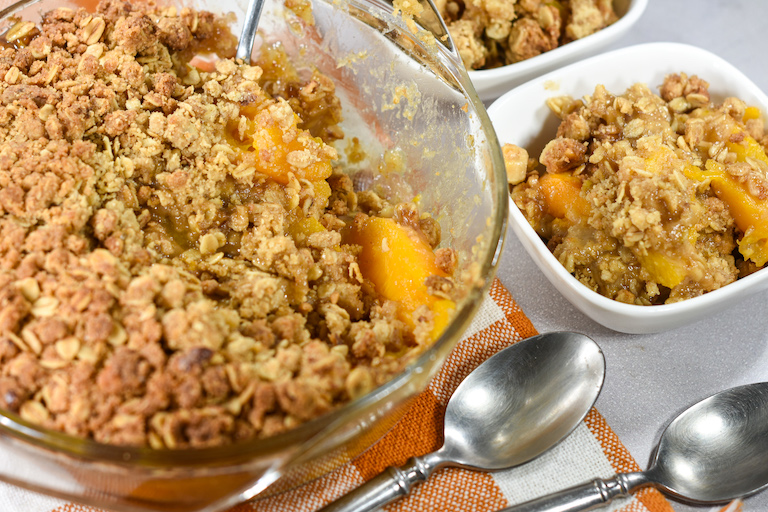 A baking dish of peach crisp with spoons