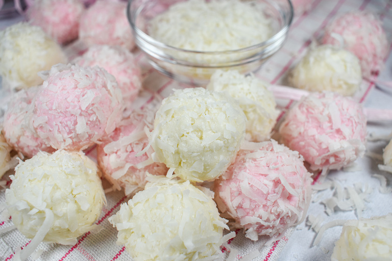 Pink and white coconut truffles on a white surface