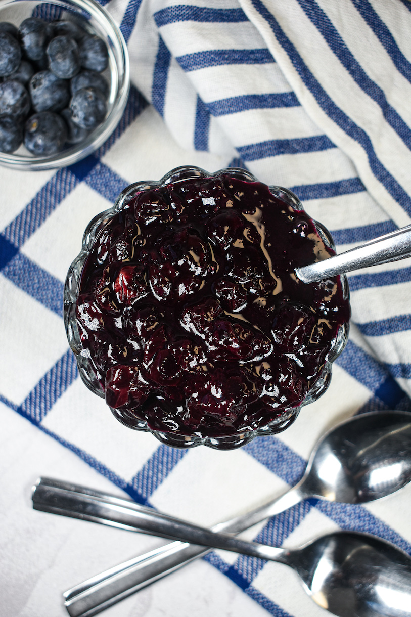 a dish of blueberry compote on a blue checkered towel