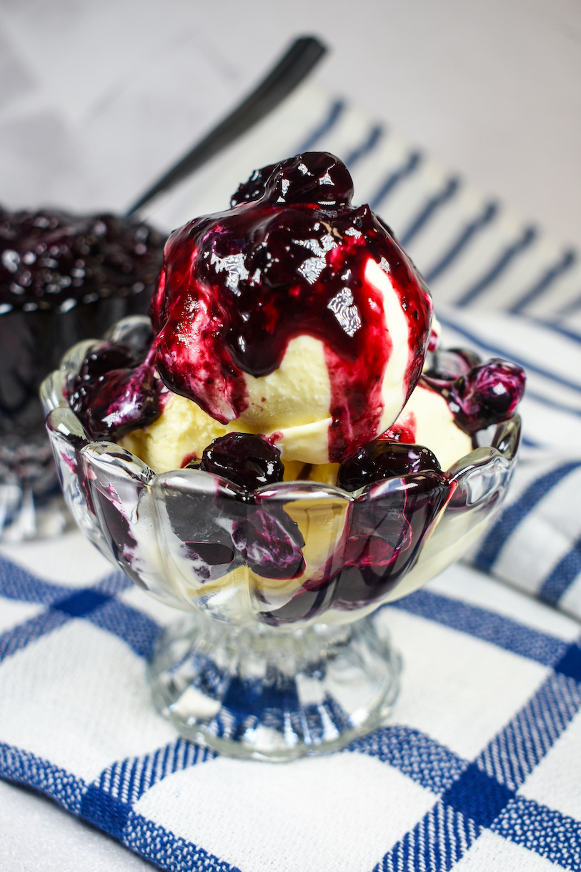 Blueberry compote spooned over scoops of homemade vanilla ice cream