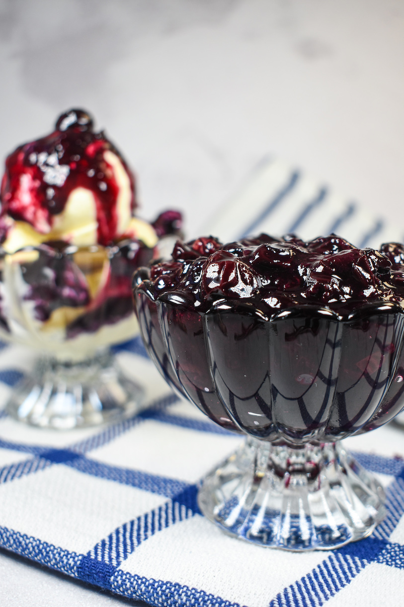 A dish of blueberry compote and compote spooned over vanilla ice cream
