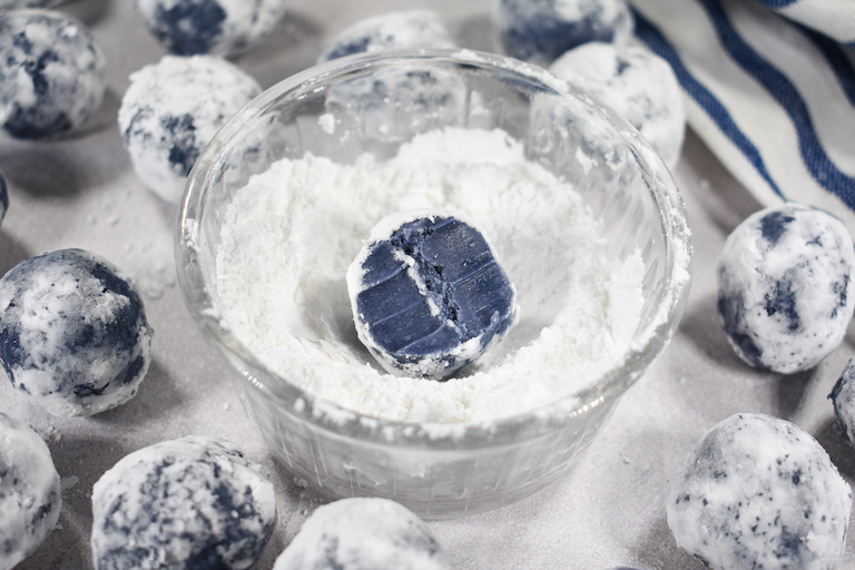A bowl of confectioner's sugar and an Earl Grey truffle with a bite missing