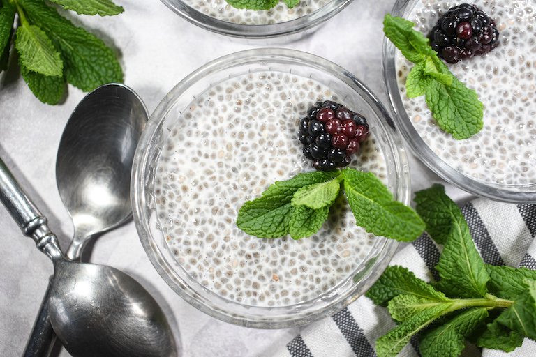 Dishes of chia pudding garnished with mint and blackberries