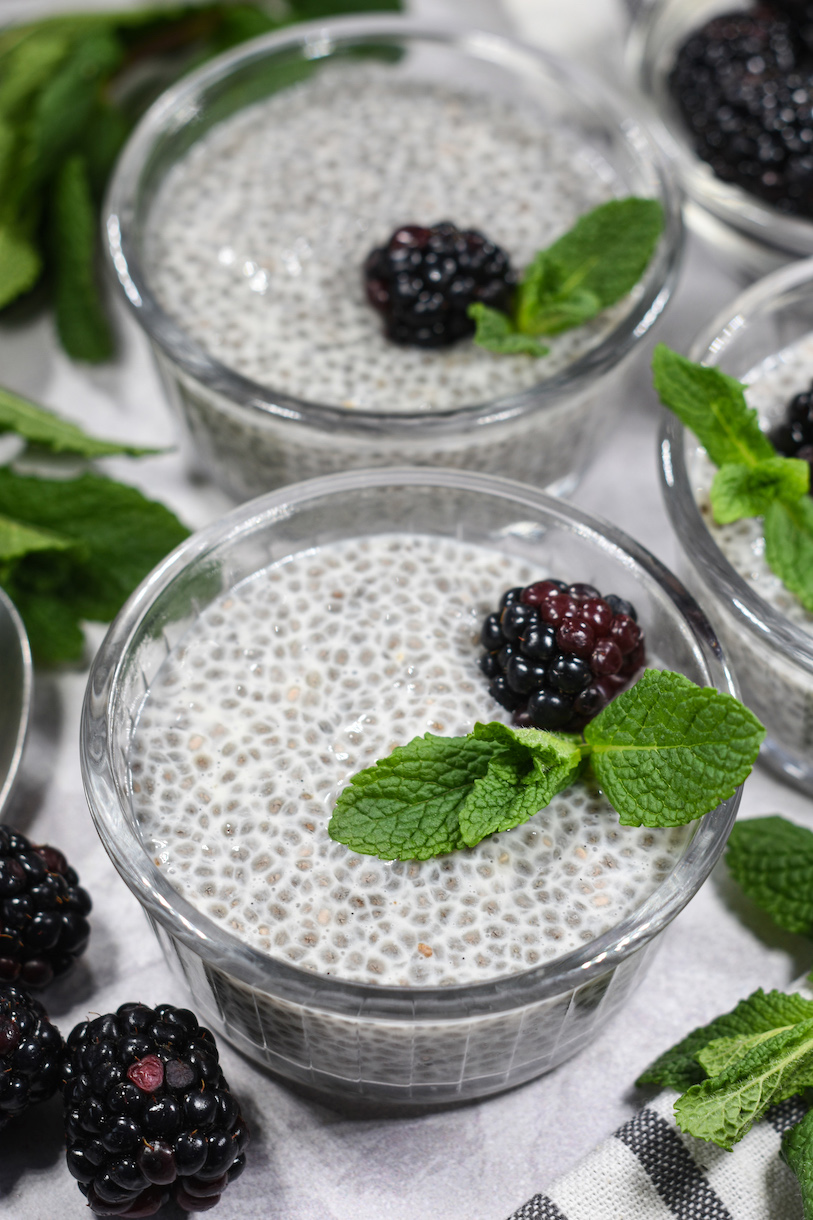 Dishes of almond milk chia seed pudding garnished with mint and blackberries