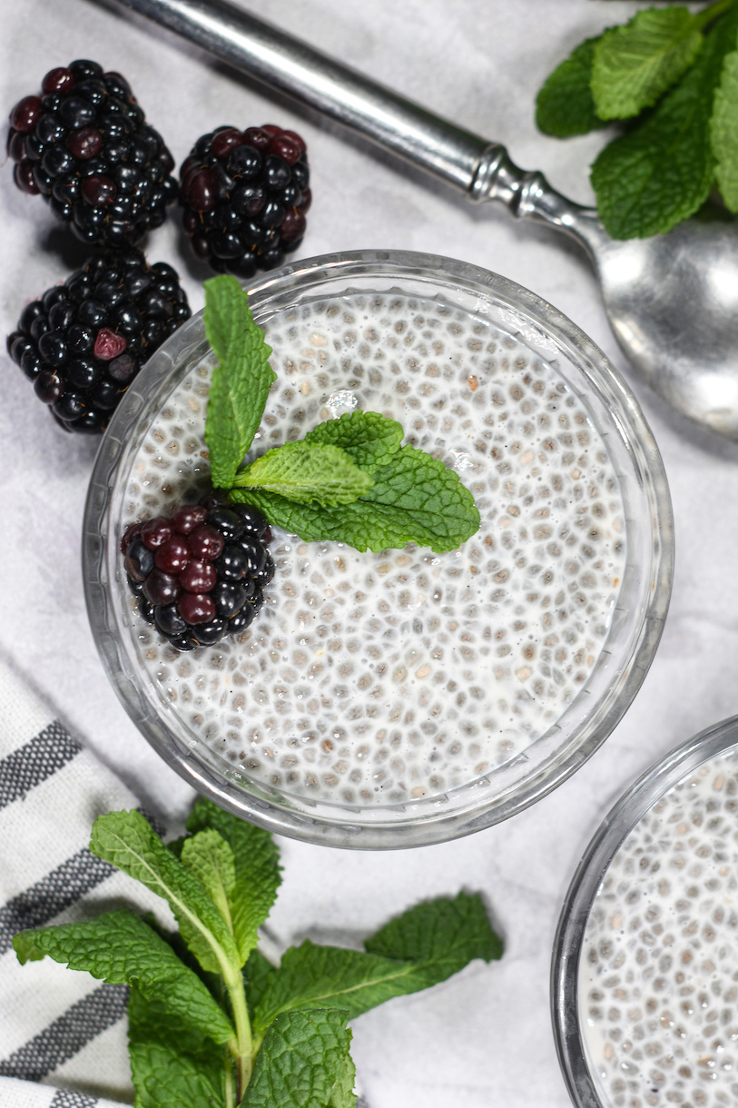 Looking down at a ramekin filled with almond milk chia pudding, garnished with berries and mint