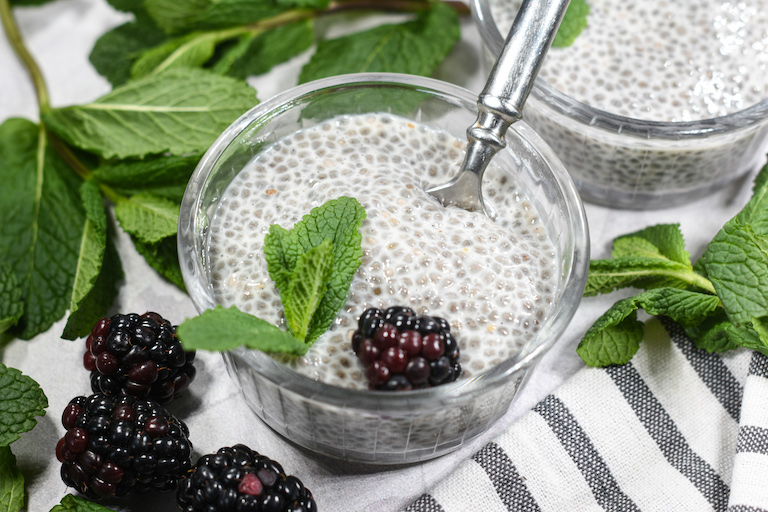 A dish of chia seed pudding garnished with blackberries and fresh mint