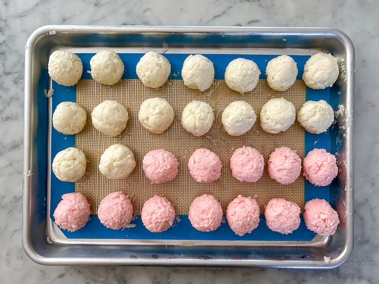 Pink and white cream cheese truffles arranged on a small tray